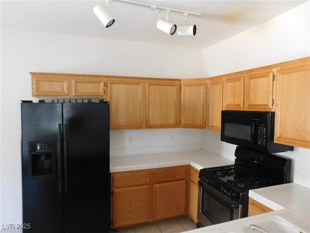 kitchen with black appliances, tile countertops, track lighting, and light tile patterned flooring