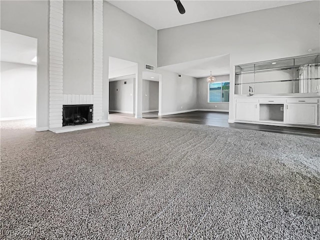 unfurnished living room featuring a high ceiling, baseboards, a fireplace, and a ceiling fan