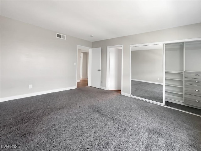 unfurnished bedroom featuring dark colored carpet, baseboards, and a closet