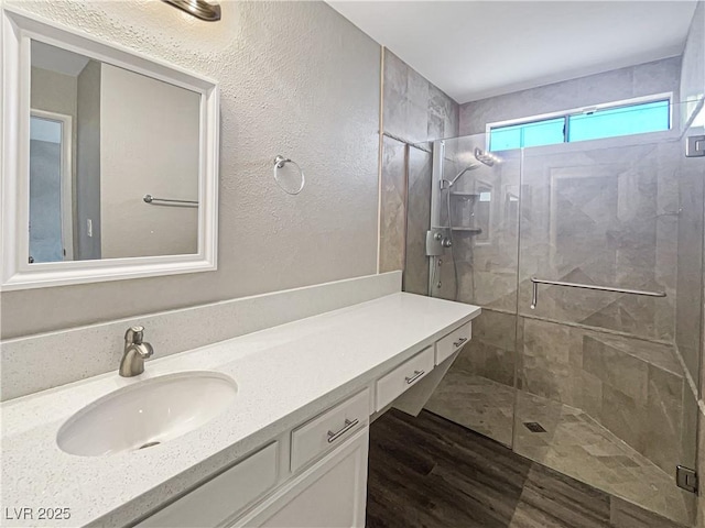 bathroom with a stall shower, wood finished floors, and vanity