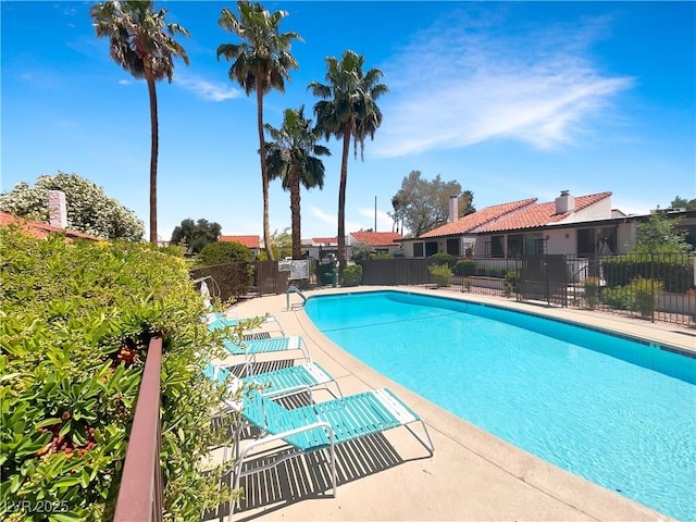 community pool with fence and a patio area