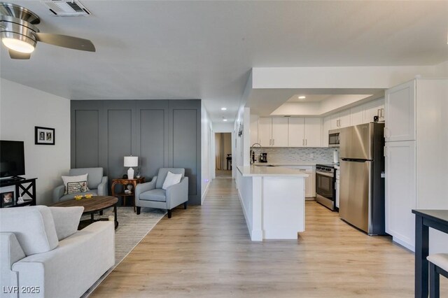 718 Nectarine Ct, Henderson, NV 89014 - kitchen featuring appliances with stainless steel finishes, open floor plan, light wood-type flooring, light countertops, and a peninsula