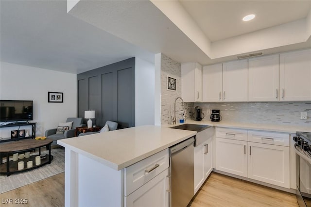 718 Nectarine Ct, Henderson, NV 89014 - kitchen featuring stainless steel dishwasher, a sink, gas stove, a peninsula, and light wood-style floors