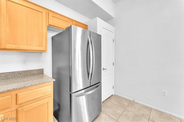 8985 S Durango Dr Unit 1110, Las Vegas, NV 89113 - kitchen with freestanding refrigerator, light tile patterned floors, baseboards, light stone countertops, and light brown cabinetry