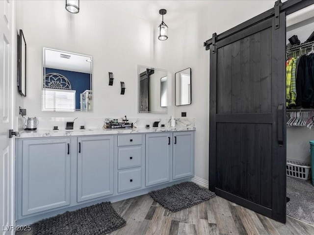 full bath featuring wood finished floors, double vanity, and a walk in closet