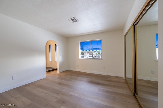 5040 Spencer St Unit D, Las Vegas, NV 89119 - unfurnished bedroom featuring light wood finished floors, arched walkways, a closet, and baseboards