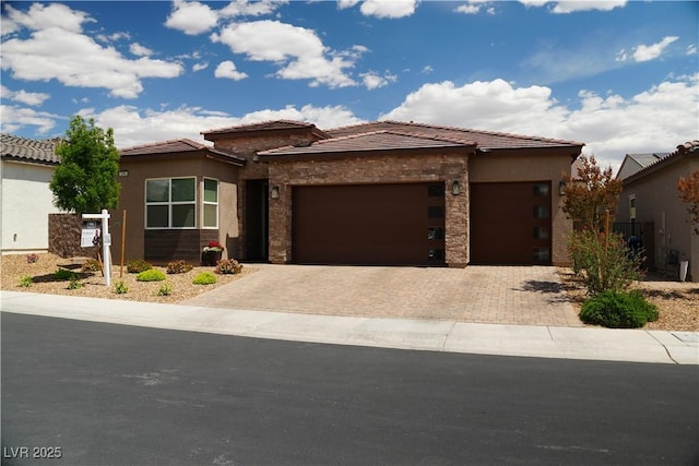 prairie-style house with decorative driveway, an attached garage, stucco siding, and stone siding