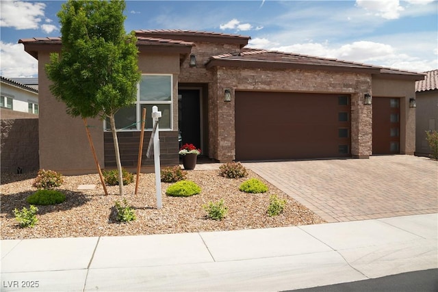 view of front of home with a garage, a tile roof, decorative driveway, and stucco siding