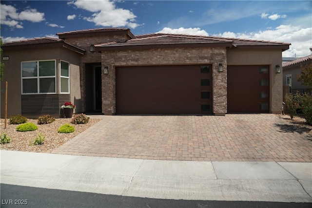 prairie-style house featuring decorative driveway, an attached garage, and stucco siding