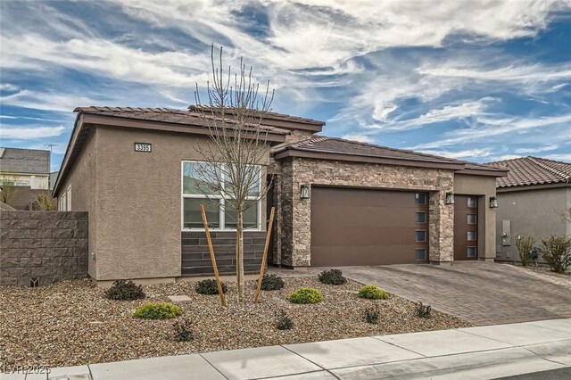 view of front of home with an attached garage, driveway, stucco siding, and a tiled roof