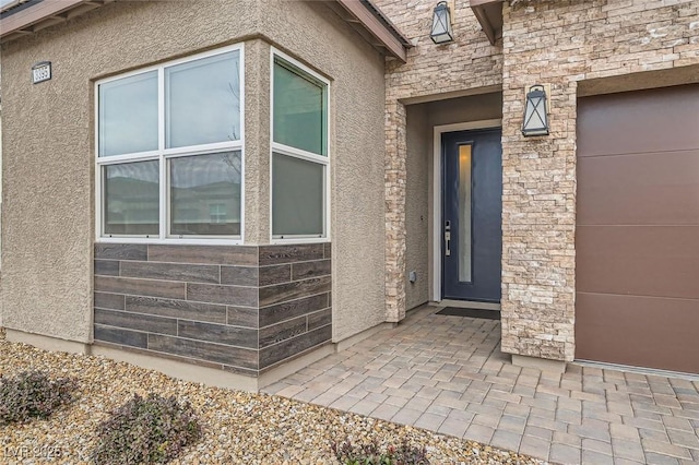 entrance to property featuring stucco siding and stone siding