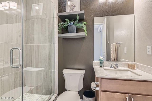 bathroom featuring toilet, a stall shower, vanity, and a textured wall