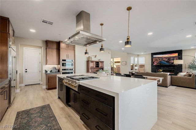 436 Crown Mesa Ave, Las Vegas, NV 89138 - kitchen with island range hood, stainless steel appliances, light wood-type flooring, open floor plan, and hanging light fixtures