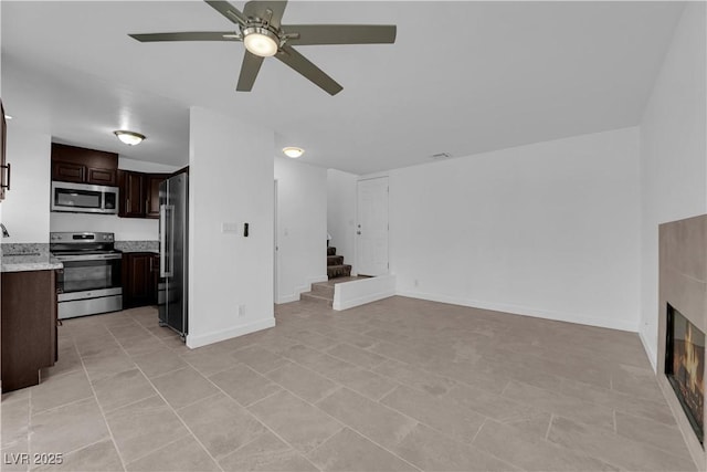 5029 Spencer St Unit D, Las Vegas, NV 89119 - unfurnished living room featuring a ceiling fan, stairway, a glass covered fireplace, and light tile patterned floors