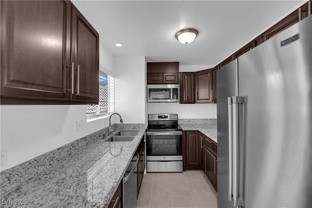 5029 Spencer St Unit D, Las Vegas, NV 89119 - kitchen featuring appliances with stainless steel finishes, a sink, light tile patterned flooring, light stone countertops, and dark brown cabinetry