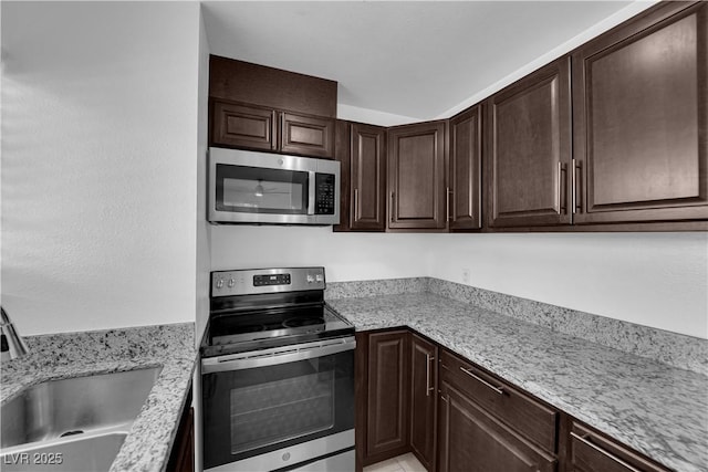 5029 Spencer St Unit D, Las Vegas, NV 89119 - kitchen with stainless steel appliances, a sink, dark brown cabinetry, and light stone counters