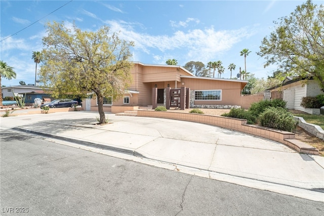 view of front of house featuring concrete driveway and fence