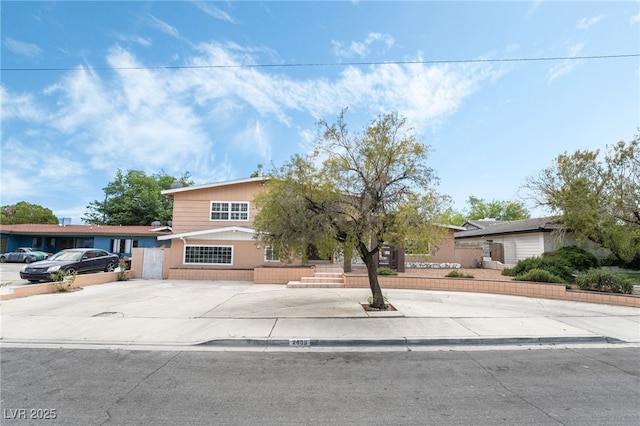 view of property hidden behind natural elements with concrete driveway