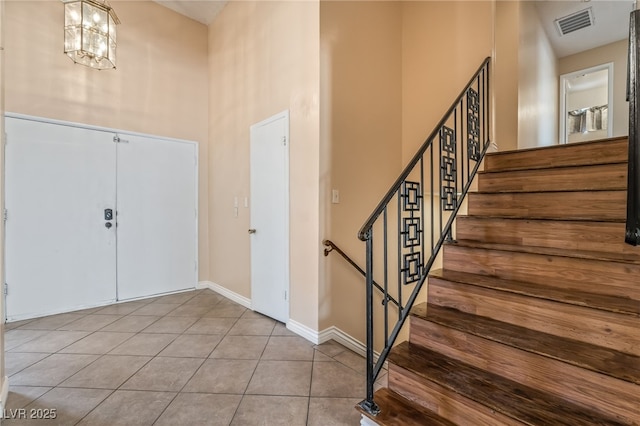 entrance foyer featuring a high ceiling, tile patterned flooring, stairway, and baseboards