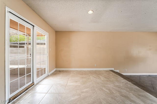 spare room with a textured ceiling and baseboards