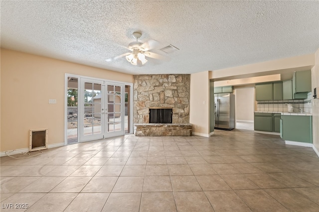 unfurnished living room featuring ceiling fan, french doors, light tile patterned flooring, a sink, and baseboards