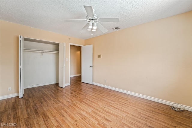 unfurnished bedroom featuring light wood finished floors, baseboards, a closet, a textured ceiling, and ceiling fan
