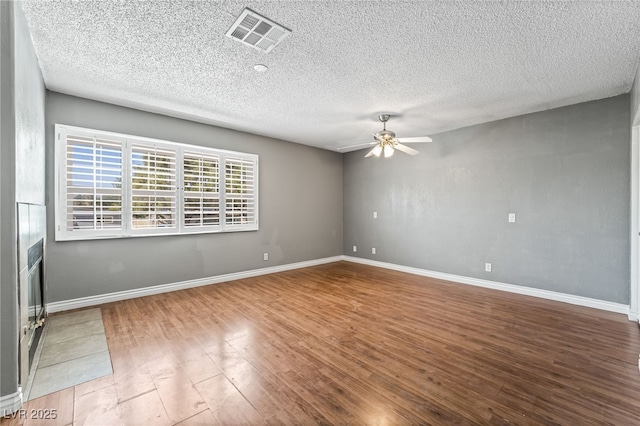 spare room with ceiling fan, wood finished floors, a textured ceiling, and baseboards