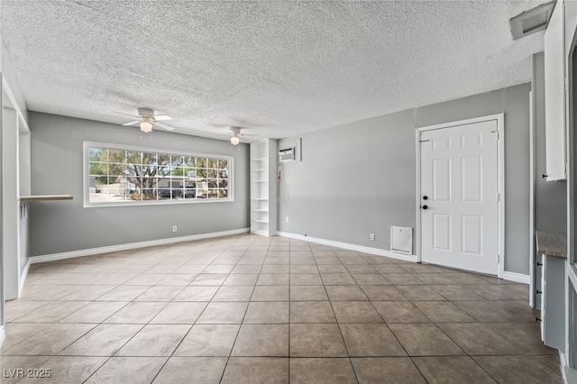 empty room featuring a ceiling fan, a textured ceiling, tile patterned floors, and baseboards