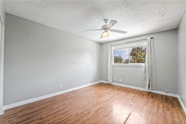 empty room with wood finished floors, ceiling fan, a textured ceiling, and baseboards