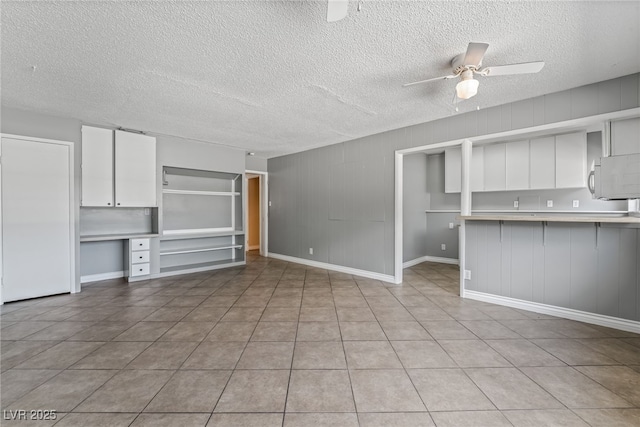 unfurnished living room featuring ceiling fan, a textured ceiling, and baseboards