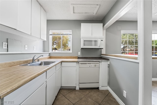 kitchen with white appliances, a sink, white cabinets, light countertops, and a textured ceiling