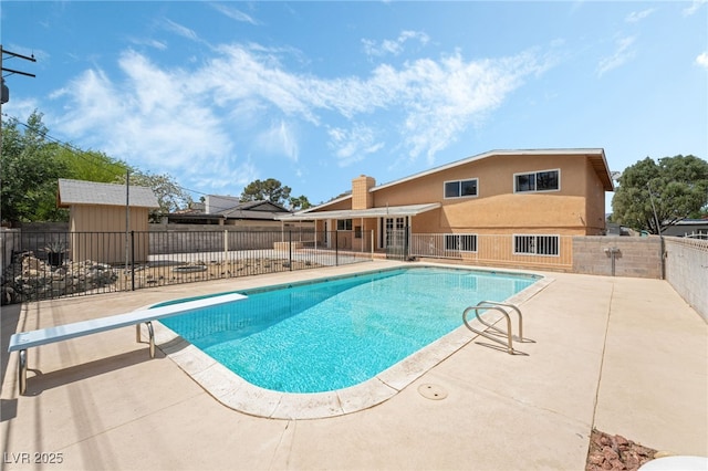 view of swimming pool featuring a patio area, fence, and a diving board