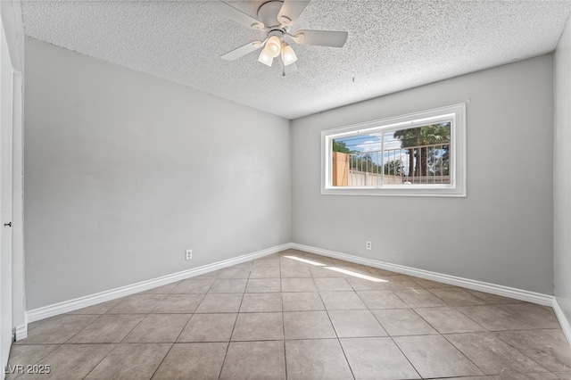 spare room with a textured ceiling, ceiling fan, tile patterned floors, and baseboards