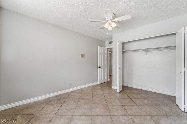 unfurnished bedroom featuring a textured ceiling, a closet, ceiling fan, baseboards, and light tile patterned flooring