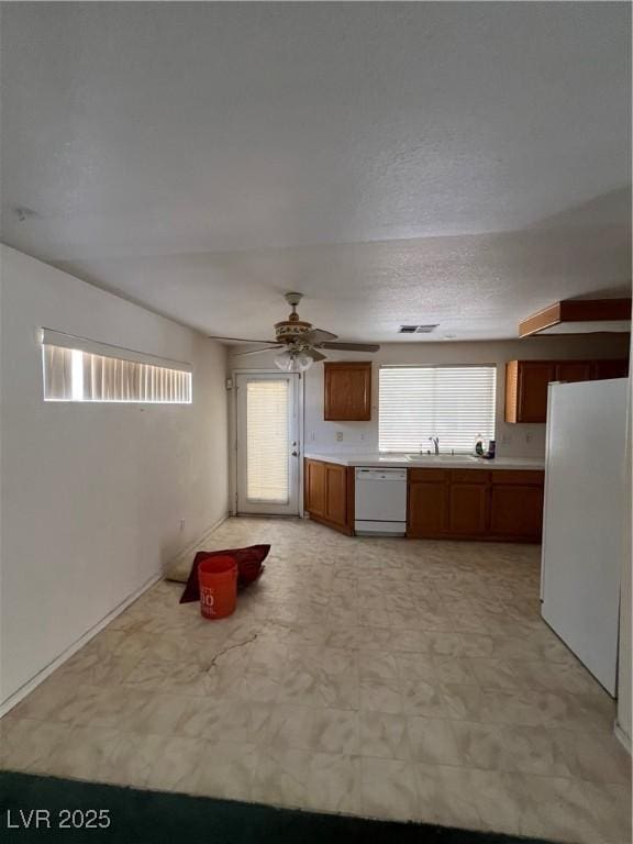 128 Appian Way, Henderson, NV 89002 - kitchen with white appliances, light countertops, brown cabinets, and ceiling fan