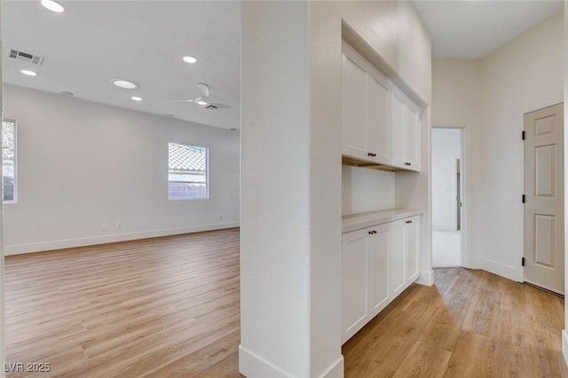 corridor with light wood-style floors, baseboards, and recessed lighting