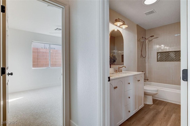 bathroom featuring tub / shower combination, vanity, toilet, and wood finished floors