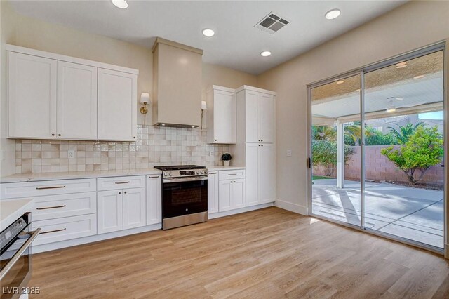 kitchen featuring stainless steel appliances, light countertops, light wood finished floors, backsplash, and recessed lighting
