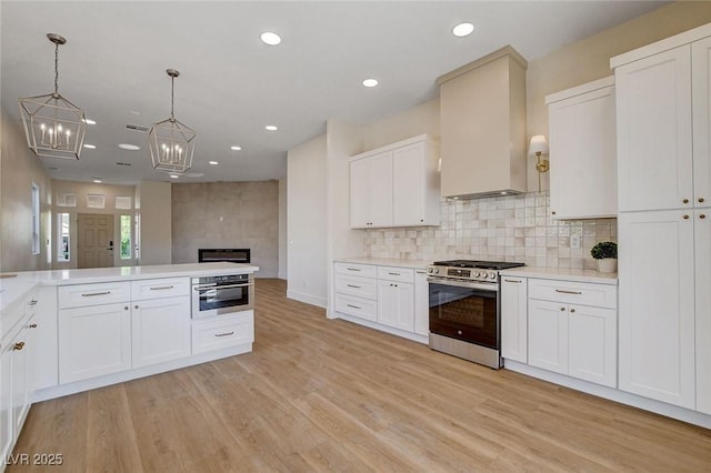 kitchen with stainless steel appliances, light wood-style floors, light countertops, white cabinetry, and decorative backsplash