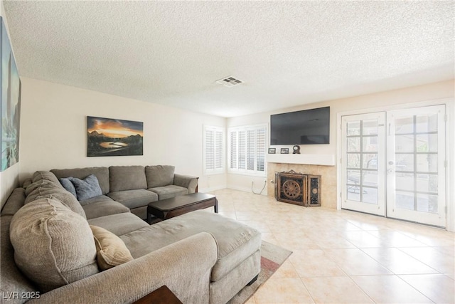 living area featuring a textured ceiling, plenty of natural light, light tile patterned flooring, a tile fireplace, and baseboards
