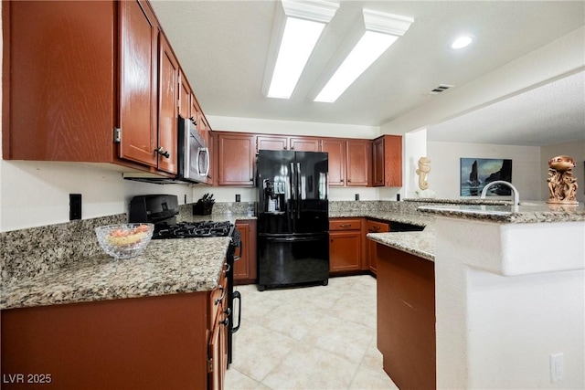 kitchen with black fridge with ice dispenser, stainless steel microwave, a peninsula, and light stone countertops