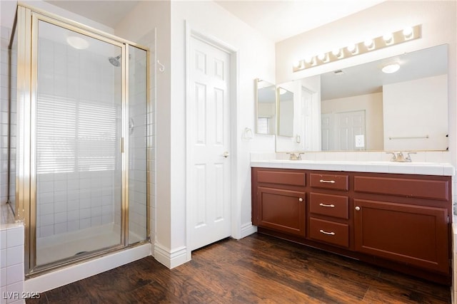 full bathroom with wood finished floors, a stall shower, and double vanity