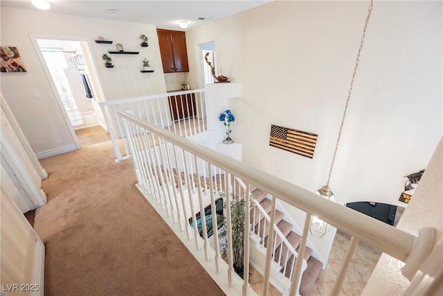 hallway featuring an upstairs landing, light colored carpet, and plenty of natural light