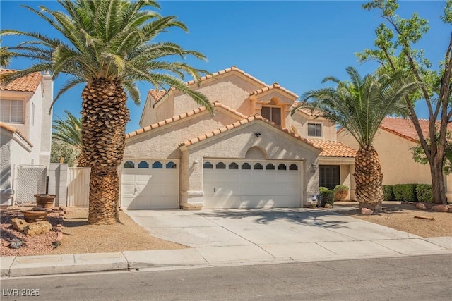 mediterranean / spanish-style home with an attached garage, a tiled roof, concrete driveway, and stucco siding
