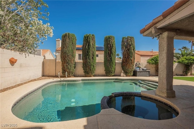 view of pool featuring a fenced backyard, a pool with connected hot tub, and a patio area