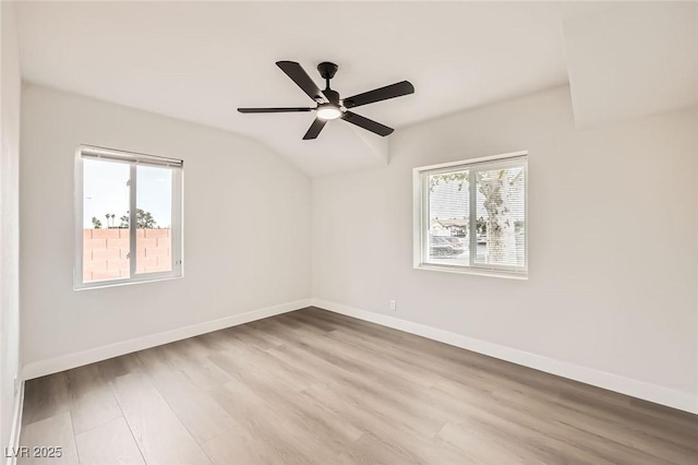 unfurnished room featuring wood finished floors, healthy amount of natural light, lofted ceiling, and baseboards