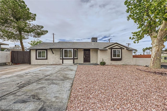 ranch-style house featuring stucco siding, fence, and a shingled roof