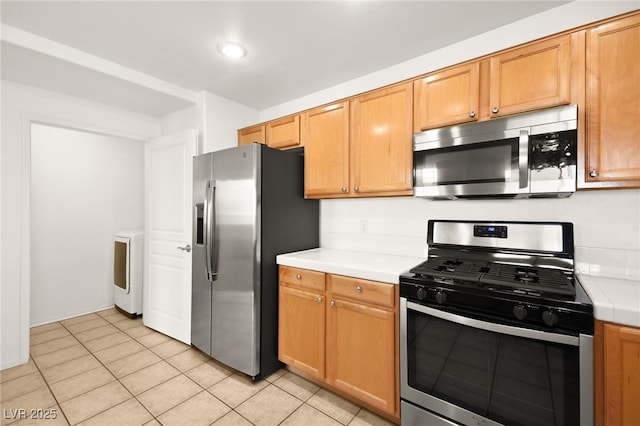 913 Duckhorn Ct Unit 204, Las Vegas, NV 89144 - kitchen featuring appliances with stainless steel finishes, washer / dryer, light tile patterned floors, recessed lighting, and tile countertops