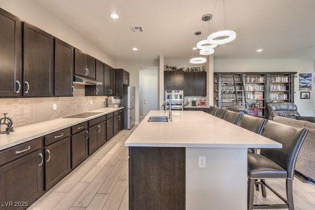 4893 E Cedar Creek Way, Pahrump, NV 89061 - kitchen featuring under cabinet range hood, freestanding refrigerator, a sink, a kitchen bar, and open floor plan