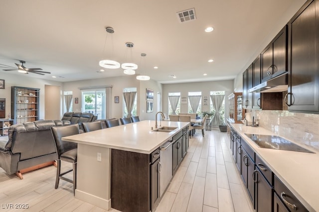 4893 E Cedar Creek Way, Pahrump, NV 89061 - kitchen with a sink, black electric stovetop, a kitchen breakfast bar, open floor plan, and light countertops
